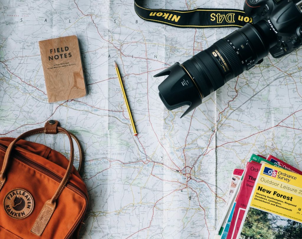 Travel planning desk with a map, camera, notebook and passport